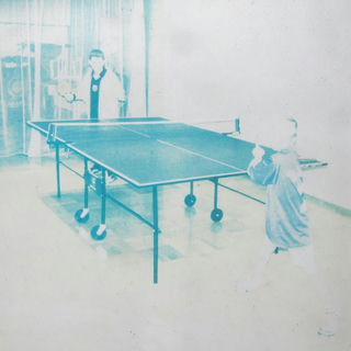 an old photo of two kids playing table tennis, blue and white, washed by the sun